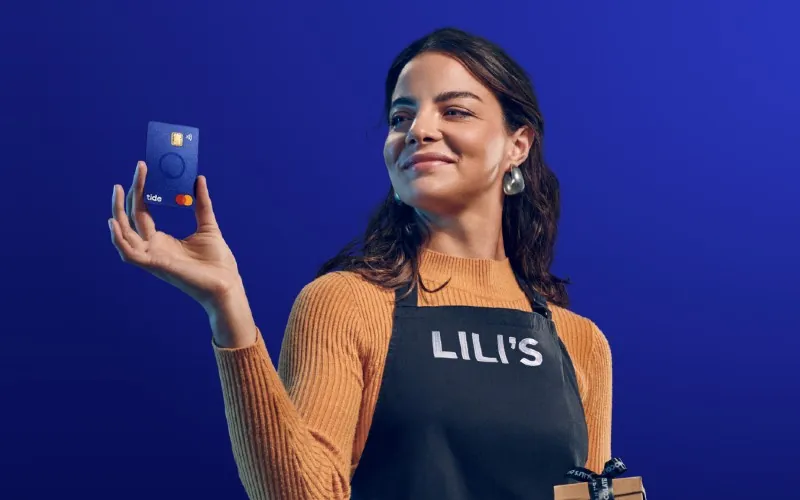 Small business owner holding a Tide business debit card